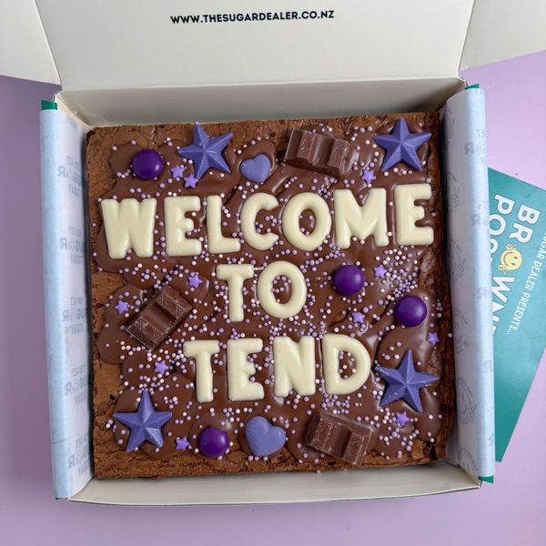 A Standard brownie reading WELCOME TO TEND in white chocolate letters